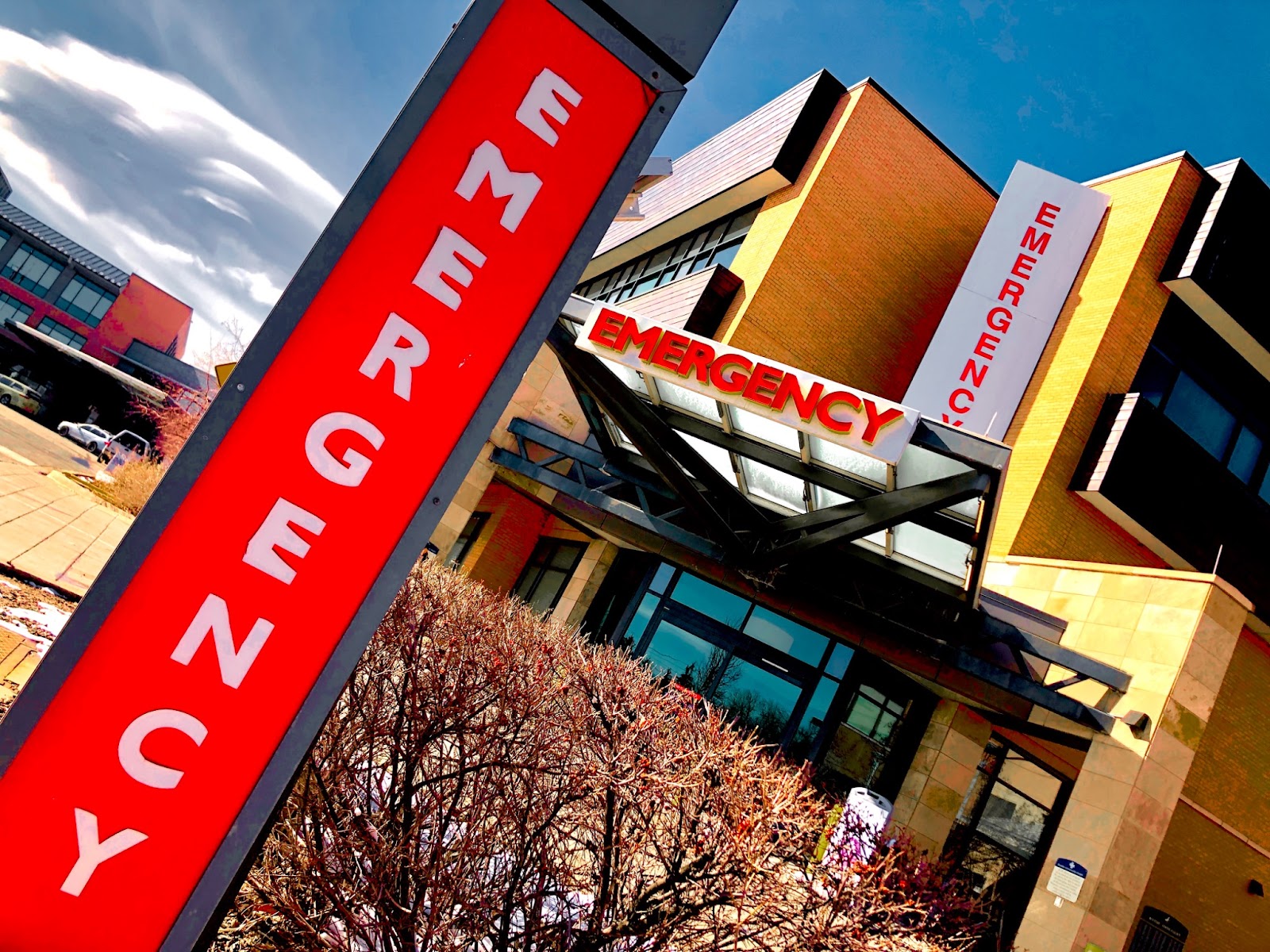 Photo of an emergency room with multiple "emergency" signs; red color enhanced.